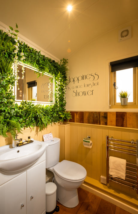 Artificial green wall panel with variegated greens of ivy, ferns, palm heads, grasses with trailing white sweet peas